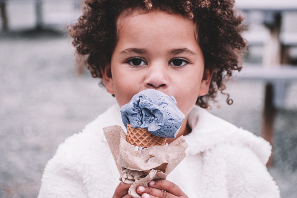 Child with curly hair enjoying ice cream to represent having a healthy relationship with food